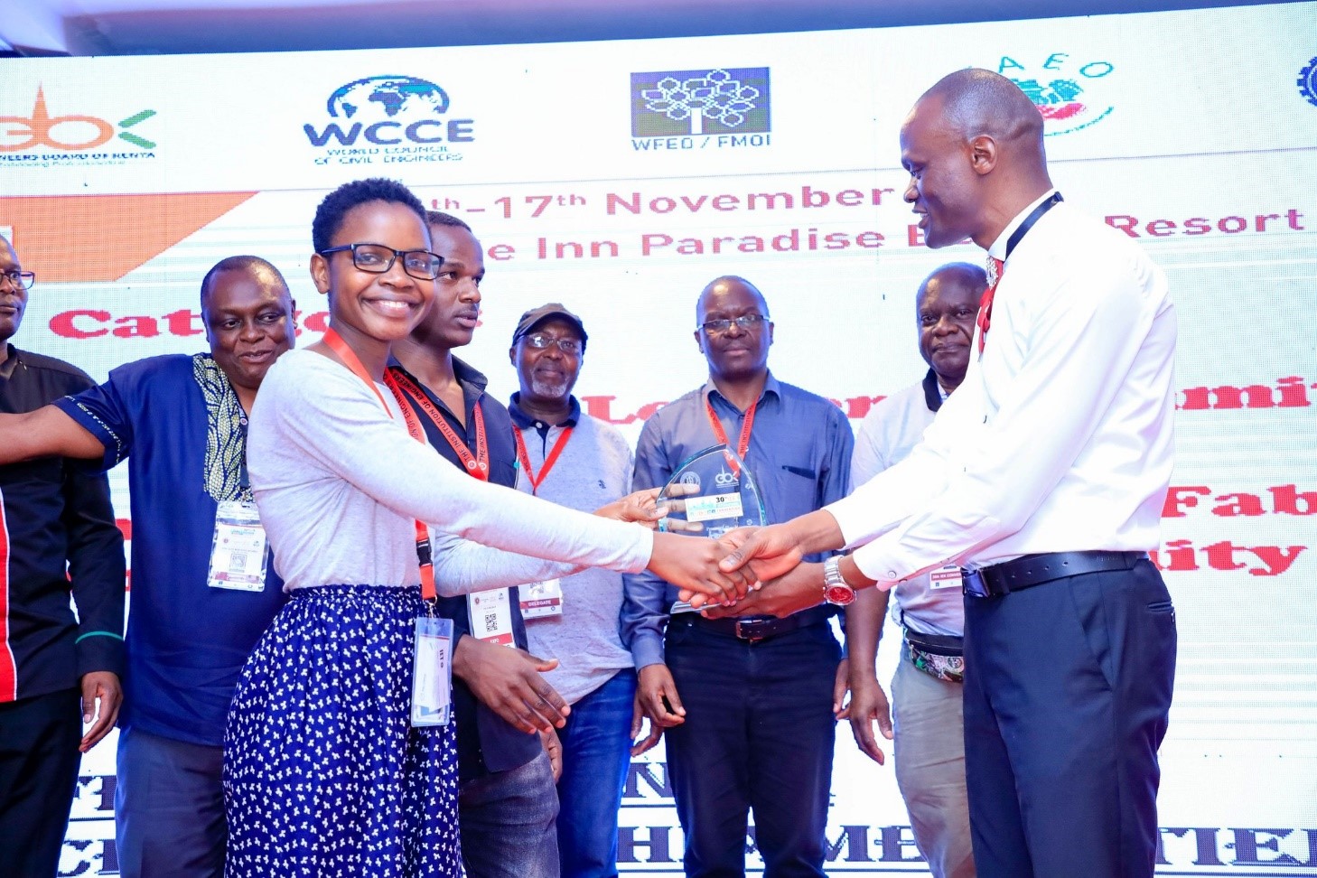Cecilia Otieno receiving 1st Prize trophy from President IEK \u2013 flanked by TUK staff and students receives the prize she and Felix Mazinza won